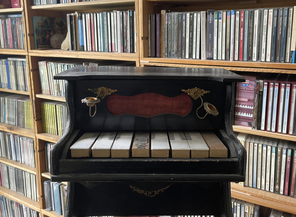 Toy piano in front of a shelf with CDs