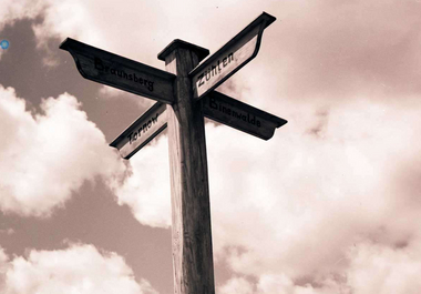 Black and white photography of a signpost in a field.