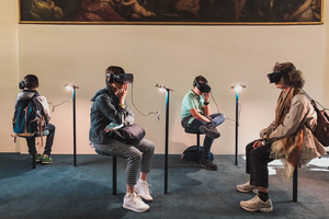 Vier Personen sitzen mit VR-Brillen vor einem Gemälde.