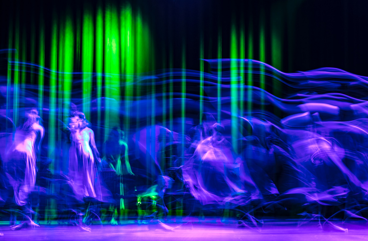 ca. 16 schattenhafte Tänzer in violett und blau vor einem abstrakten grün-schwarzen Hintergrund
about six shadowy dancers in velvet and blue in front of an abstract black and green background